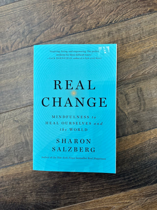 Book titled 'Real Change' by Sharon Salzberg on a wooden surface